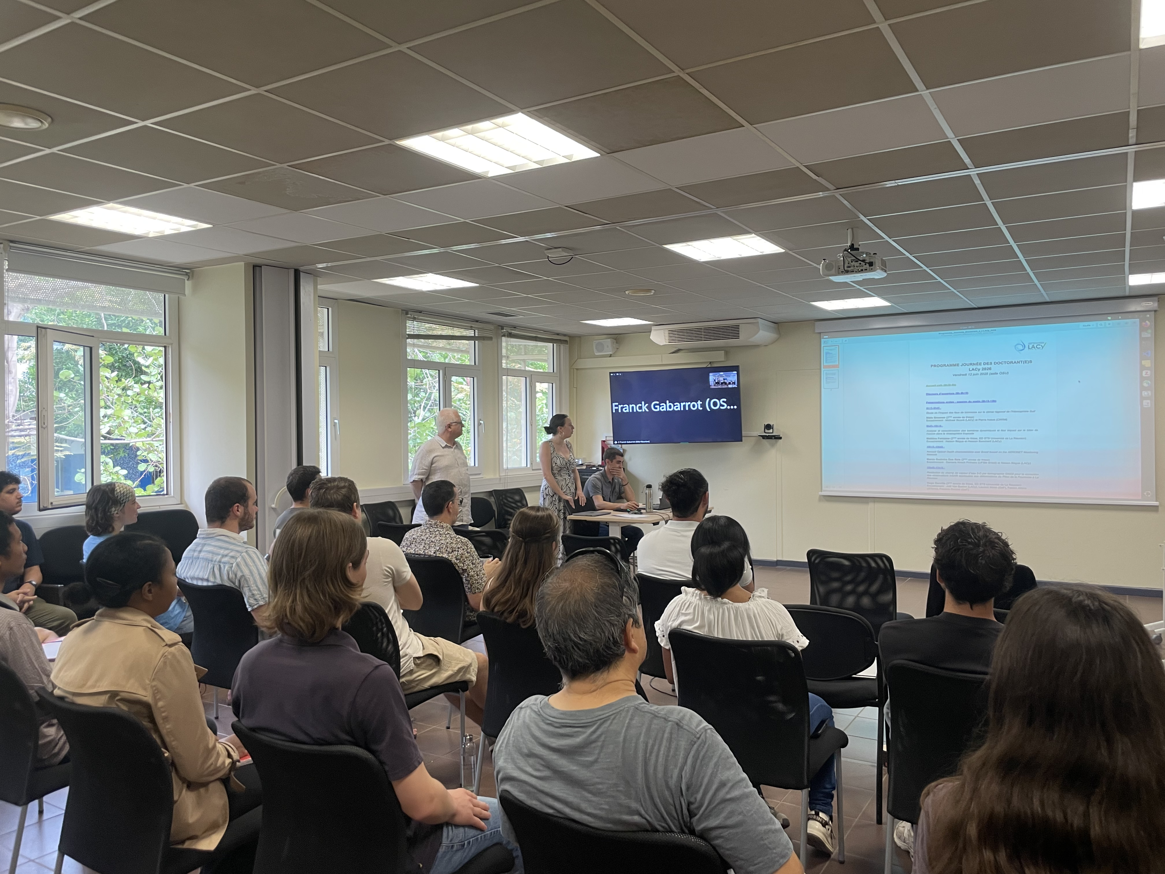 Room full of lab members and presentation of the programme of the PhD day at the Laboratory.